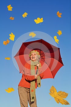 Happy woman with umbrella and falling leaves