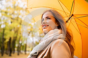 Happy woman with umbrella walking in autumn park