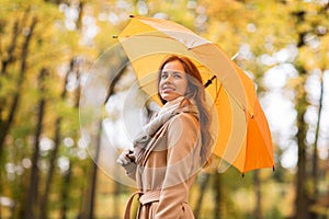 Happy woman with umbrella walking in autumn park