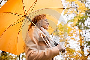 Happy woman with umbrella walking in autumn park