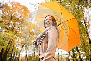 Happy woman with umbrella walking in autumn park