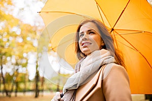 Happy woman with umbrella walking in autumn park