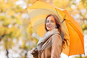 Happy woman with umbrella walking in autumn park