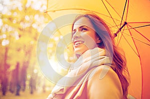 Happy woman with umbrella walking in autumn park