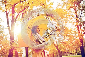 Happy woman with umbrella walking in autumn park