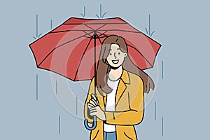 Happy woman with umbrella walks in rain along autumn street and looks at screen with wide smile