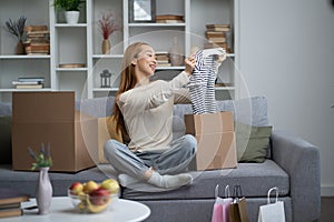 Happy Young Woman Unpacking Clothes in New Home photo