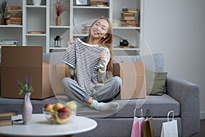 Happy Young Woman Unpacking Clothes In New Home Living Room photo