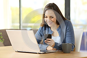 Happy woman uses phone and laptop at home