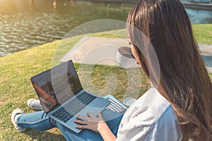 Happy woman using laptop in park, intentionally toned