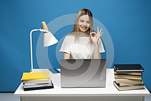 Happy woman using laptop and showing ok sign to a friends, colleagues or to a clients that everything is ok and looking