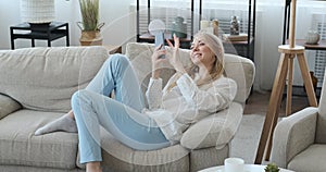 Happy woman using mobile phone on sofa at home