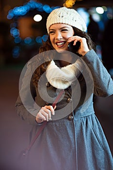Happy woman using a mobile phone in the street in winter. Christmas communication people concept