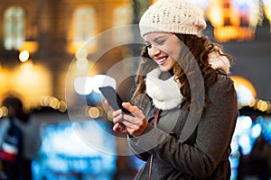 Happy woman using a mobile phone in the street in winter. Christmas communication people concept