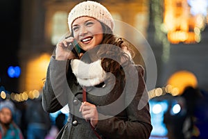 Happy woman using a mobile phone in the street in winter. Christmas communication people concept