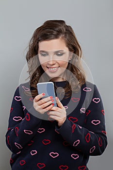Happy woman using smadrtphone, texting and smiling on gray backgroun