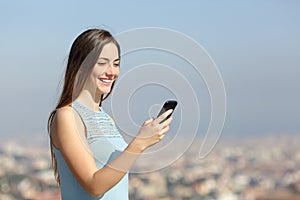 Happy woman using a smart phone in a city outskirts photo
