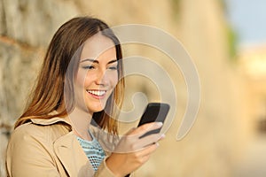 Happy woman using a smart phone in an old town