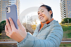 Happy woman using the smart phone outdoors. Real people and technology concept.