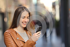 Happy woman using a smart phone in the street