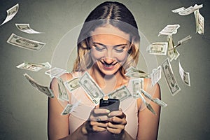 Happy woman using smartphone with dollar bills flying away from screen