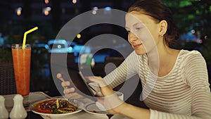 Happy woman using smartphone and messaging sitting in restaurant at night