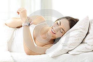 Happy woman using a smartwatch on the bed