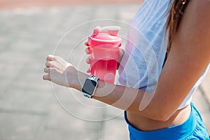 Happy woman using smartwatch for checks results in fitness app. Female athlete wearing sport tracker wristband arm. Healthy