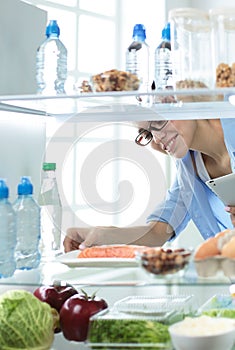 Happy Woman With Vegetables In Front Of Open Refrigerator