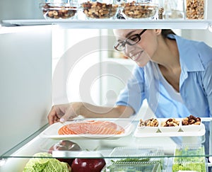 Happy Woman With Vegetables In Front Of Open Refrigerator