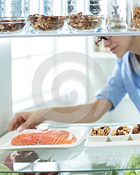 Happy Woman With Vegetables In Front Of Open Refrigerator