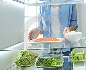 Happy Woman With Vegetables In Front Of Open Refrigerator