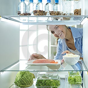 Happy Woman With Vegetables In Front Of Open Refrigerator