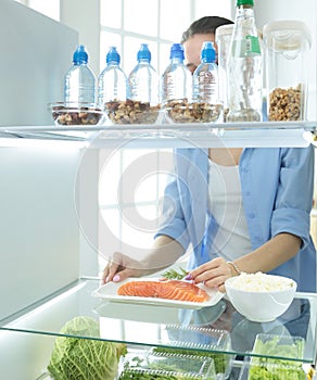 Happy Woman With Vegetables In Front Of Open Refrigerator