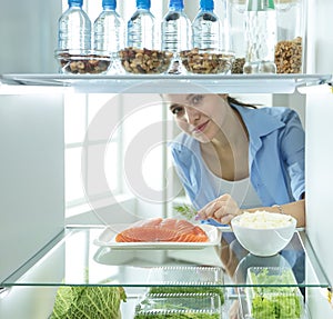 Happy Woman With Vegetables In Front Of Open Refrigerator