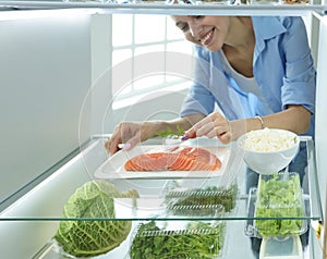 Happy Woman With Vegetables In Front Of Open Refrigerator