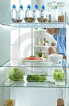 Happy Woman With Vegetables In Front Of Open Refrigerator