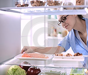 Happy Woman With Vegetables In Front Of Open Refrigerator