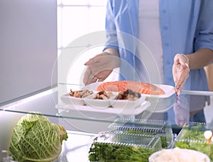 Happy Woman With Vegetables In Front Of Open Refrigerator