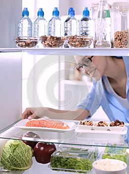 Happy Woman With Vegetables In Front Of Open Refrigerator