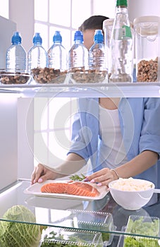 Happy Woman With Vegetables In Front Of Open Refrigerator