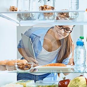 Happy Woman With Vegetables In Front Of Open Refrigerator