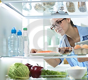 Happy Woman With Vegetables In Front Of Open Refrigerator