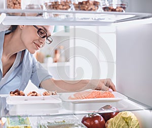 Happy Woman With Vegetables In Front Of Open Refrigerator