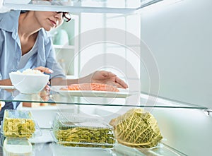 Happy Woman With Vegetables In Front Of Open Refrigerator