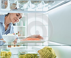 Happy Woman With Vegetables In Front Of Open Refrigerator