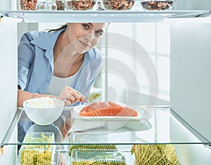 Happy Woman With Vegetables In Front Of Open Refrigerator