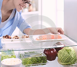 Happy Woman With Vegetables In Front Of Open Refrigerator