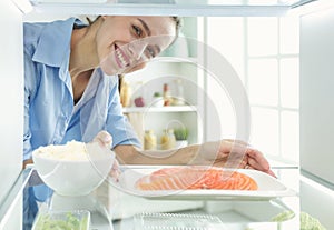 Happy Woman With Vegetables In Front Of Open Refrigerator