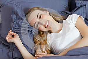 Happy woman waking up on the bed in the morning